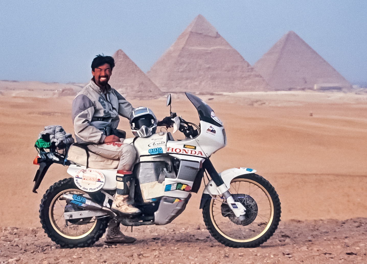 ピラミッドを前にバイクにまたがる周生さん